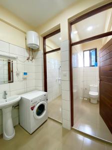 a bathroom with a washing machine and a sink at CITY Que2ens in Arusha