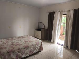 a bedroom with a bed and a dresser and a window at Paraíso chama in Jaguaruna