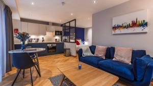 a living room with a blue couch and a kitchen at Farringdon Serviced Apartments by LovelyStay in London
