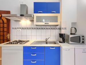 een keuken met blauwe kasten, een wastafel en een magnetron bij Apartment Romantika-3 by Interhome in Rovinj