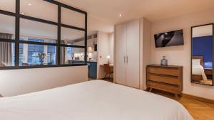 a bedroom with a large white bed and windows at Farringdon Serviced Apartments by LovelyStay in London