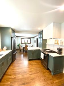 a large kitchen with green cabinets and wooden floors at Luxe & Serene Gem, Arches Cottage Retreat in Grand Rapids