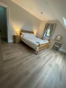 um quarto com uma cama e piso de madeira em Rosie's Bar Apartment - em Aughagault Big