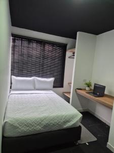 Un dormitorio con una cama y una computadora portátil en un escritorio. en Hostal Capital HEU, en Bogotá