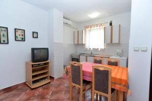 een kamer met een tafel en stoelen en een televisie bij Apartments Slavica 590 in Fažana