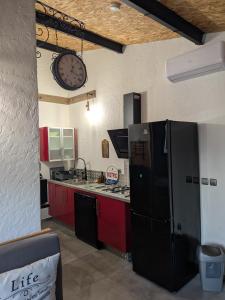 a kitchen with a black refrigerator and a clock on the wall at L'Attellu di Babbu in Lecci