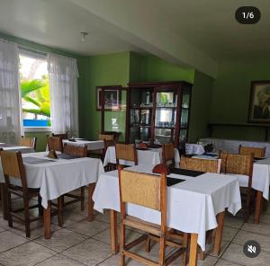 a restaurant with white tables and chairs and green walls at Pousada do Deck in Alcobaça