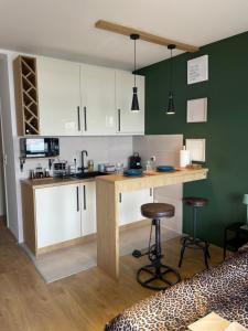 a kitchen with white cabinets and a counter with stools at Check In Apartment Kladovo in Kladovo