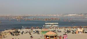 a crowd of people on a beach with boats in the water at Shashi Bhawan in Prayagraj