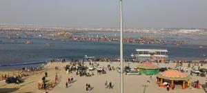 a crowd of people on a beach with boats in the water at Shashi Bhawan in Prayagraj