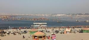 a crowd of people on a beach with boats in the water at Shashi Bhawan in Prayagraj