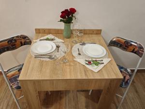 a wooden table with two plates and a vase of roses at Apartament Luca in Călimăneşti