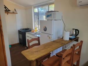a kitchen with a table and a white refrigerator at Ananda Lodge A special haven in Punta Del Diablo