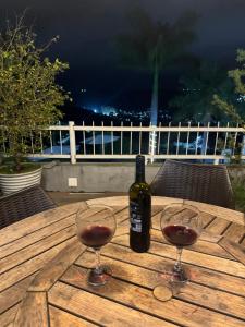 a bottle of wine and two glasses on a wooden table at Apt Alto da Serra Villas - Bananeiras in Bananeiras