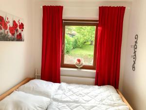 a bedroom with red curtains and a bed and a window at Fewo An Der Ostsee in Klütz +6 photos
