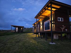 a wooden house with lights on the side of a field at Cabañas AlSur Patagonia in Puerto Natales