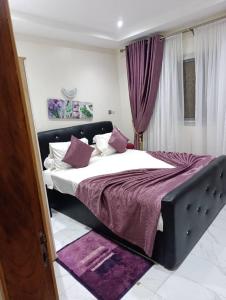 ein Schlafzimmer mit einem großen Bett mit lila Bettwäsche in der Unterkunft Résidence Angéline 4 studios in Yassa