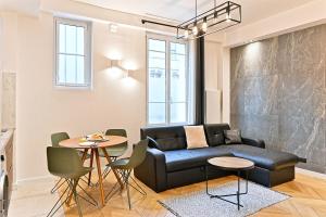 ein Wohnzimmer mit einer schwarzen Couch und einem Tisch in der Unterkunft Studio Raffiné près de la Seine Paris 16ème in Paris