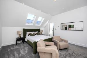 a bedroom with a large bed and two chairs at Luxe Retreat 5-Bedroom Designer Home Pool & Cinema in Brighton & Hove