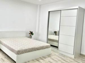 une chambre blanche avec un lit et un miroir dans l'établissement Apartament 3 cam Grand Arena, à Bucarest