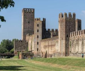 a castle with two towers and a grass field at Il Torrione di Lara locazione turistica in Montagnana