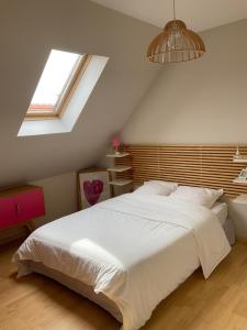 a bedroom with a large white bed and a window at La Lutine in Luc-sur-Mer
