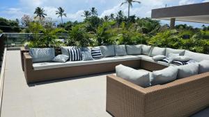 a couch sitting on a patio with pillows at Flat Luxo 104A Malia em Muro Alto Porto de Galinhas in Ipojuca