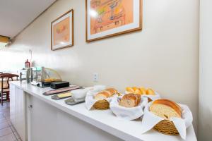 a white counter with bread and baskets of bread at Hotel Express Confort in São Leopoldo