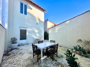 a patio with a table and chairs next to a building at Bord de mer 60 m - Charmante Maison 5 personnes in Fouras