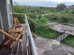 a balcony with two wooden chairs sitting on a porch at Complejo DYE in Bialet Massé
