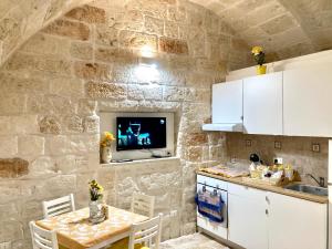 a kitchen with a table and a tv on a stone wall at Antica Pietra in Polignano a Mare
