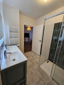 a bathroom with a sink and a glass shower at L'authentique - Appartement 4 in Loudéac