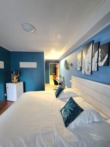 a bedroom with a large white bed with blue walls at Hôtel des Argousiers in Ambleteuse