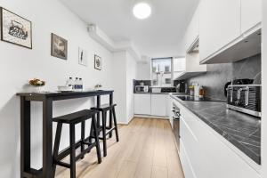 a kitchen with a black counter top and white cabinets at The Queensborough Apartments by Hyde Park in London