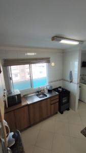 a kitchen with a sink and a stove at Half Beach Apartment - Itapema in Itapema