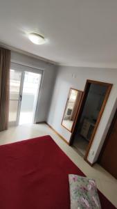 a bedroom with a red bed and a mirror at Half Beach Apartment - Itapema in Itapema