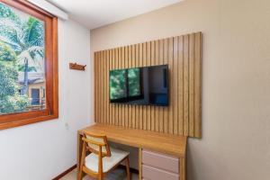 a room with a desk with a television on a wall at condominio viva barra barra grande casa 136 in Marau +11 photos