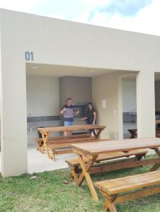 two people standing in a room with picnic tables at Apartamento completo , bem localizado in Pelotas