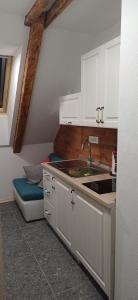 a kitchen with white cabinets and a sink and a bench at HIŠA MARGIT, Studio APARTMA in Rateče