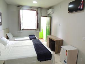 a bedroom with two beds and a television in it at Hotel Continental - Próximo ao Mercado Central, Mercado Novo e a Rodoviária in Belo Horizonte