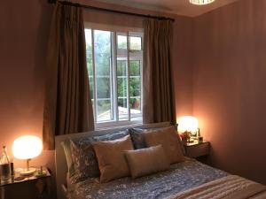 a bedroom with a bed with two lamps and a window at Leafy Suburban Bed and Breakfast in Northwood