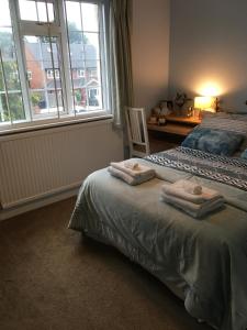 a bedroom with a bed with two towels on it at Leafy Suburban Bed and Breakfast in Northwood