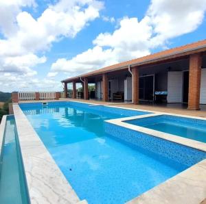 a swimming pool in front of a house at Nosso Recanto Alicia e Miguel in Ibiúna