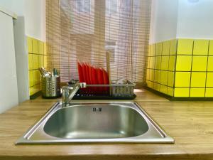 a stainless steel sink in a kitchen with yellow tiles at Апартаменти в центрі старого Львова in Lviv