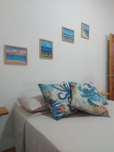 a pillow on a bed with pictures on the wall at Casa Isla Paraíso in Mazunte