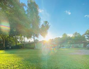 a sun is setting in a yard with trees at Chácara Leão Dourado in Pôrto Feliz