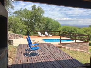 a deck with two chairs and a swimming pool at Cabaña EL GALLO in Villa General Belgrano