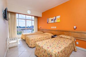 a hotel room with two beds and a window at Hotel Express Confort in São Leopoldo