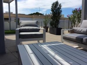 a patio with a bench and a couch on a balcony at Les plages du Grand Vallen - Résidence Château Leenhardt in Le Grau-du-Roi