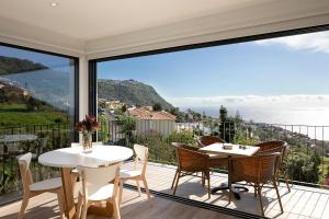 a balcony with tables and chairs and a view of the ocean at Marco 4 Seasons- Summer in Arco da Calheta